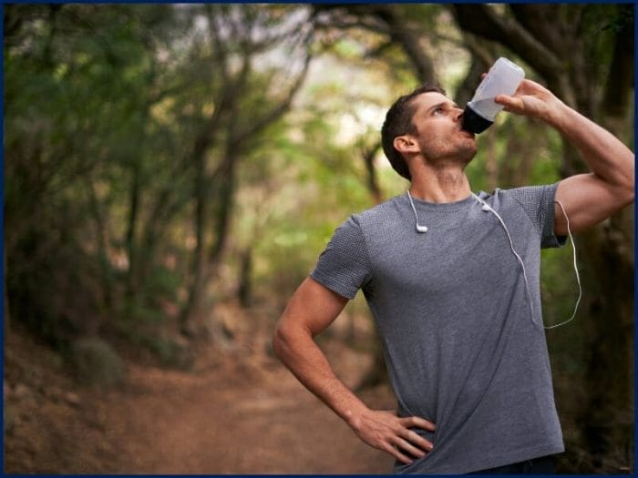 Image of a man drinking a glass of water to stay hydrated.