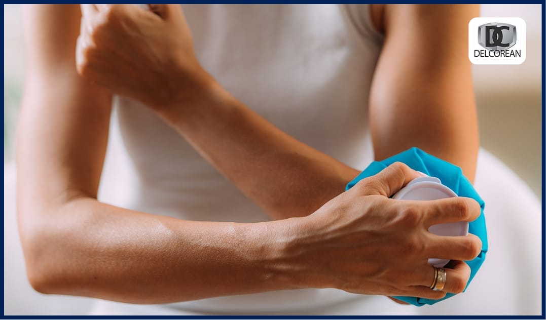 Person wearing white applying a cold compress to their elbow for pain relief