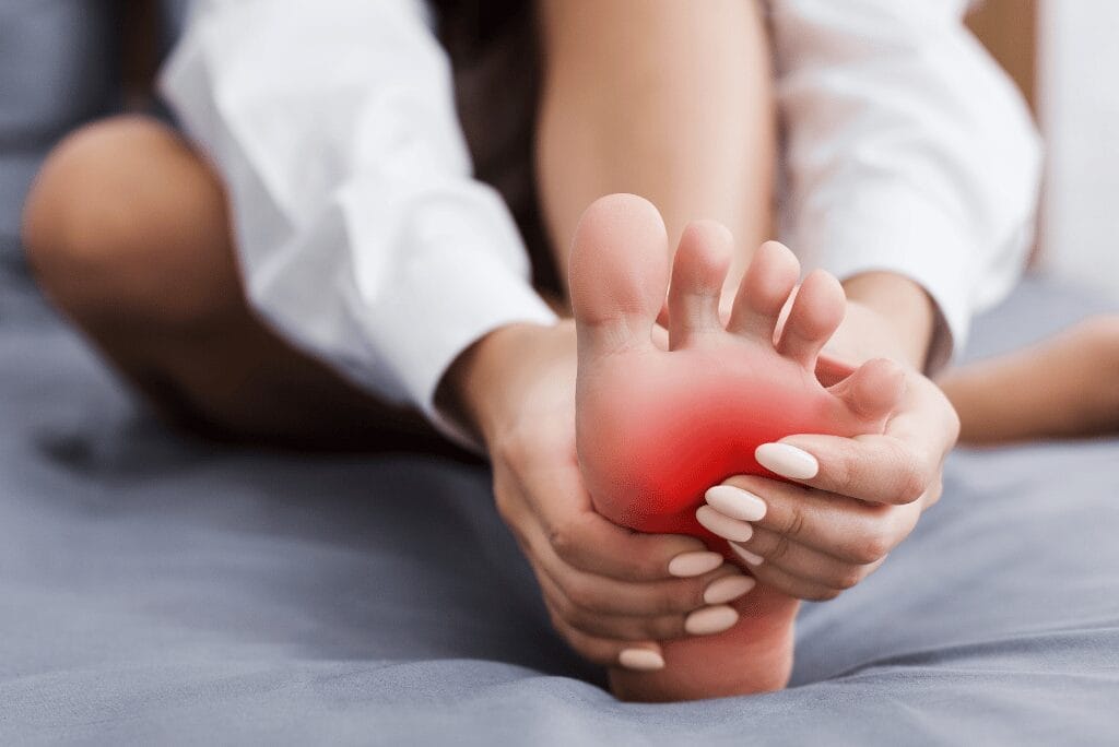Person holding foot with cramp pain at night in bed